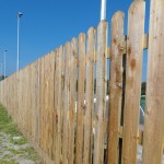Green pressure treated softwood pickets shown in a garden fence