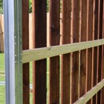 A DuraPost commercial fence post shown with wooden rails and boards attached