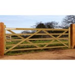 Charltons Forester wooden gate with 5 bars hung across a field entrance with metal hinges and hung on square posts